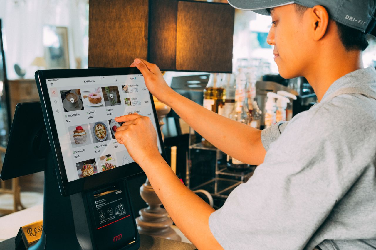 heros-img A cafe worker navigating a modern touchscreen system to manage orders efficiently.